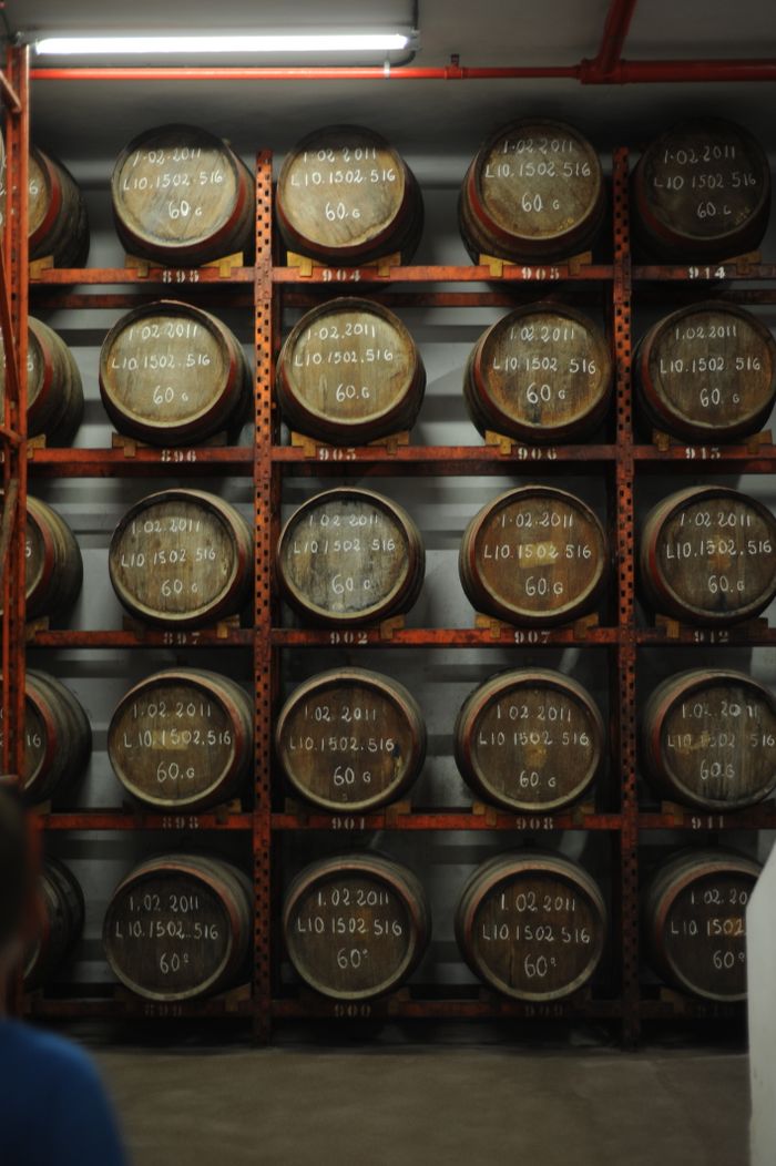 A vertically stacked arrangement of whiskey barrels in an indoor storage warehouse.